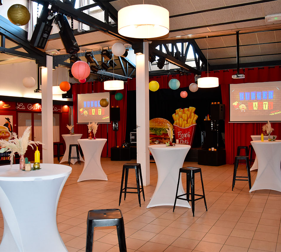 Soirée à thème Burger Party dans la salle Spectacle du Relais du Moulin Neuf, décorée avec mange-debout et projecteurs