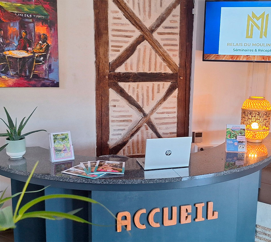 Accueil du Relais du Moulin Neuf avec comptoir, brochures et écran dédié aux séminaires.